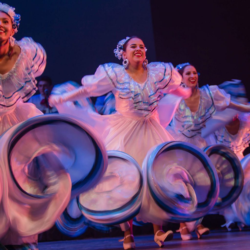 A group of Flamenco dancers in colorful dresses on stage