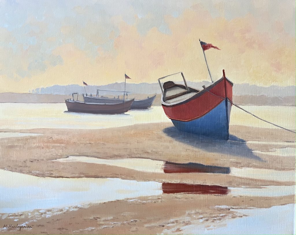 A read and blue sailboat at lowtide on the sand.
